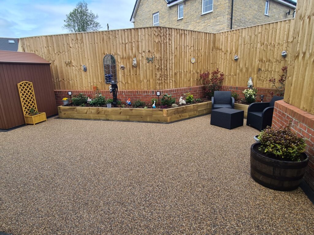 Golden resin patio with sleeper planters, seating and timber fencing