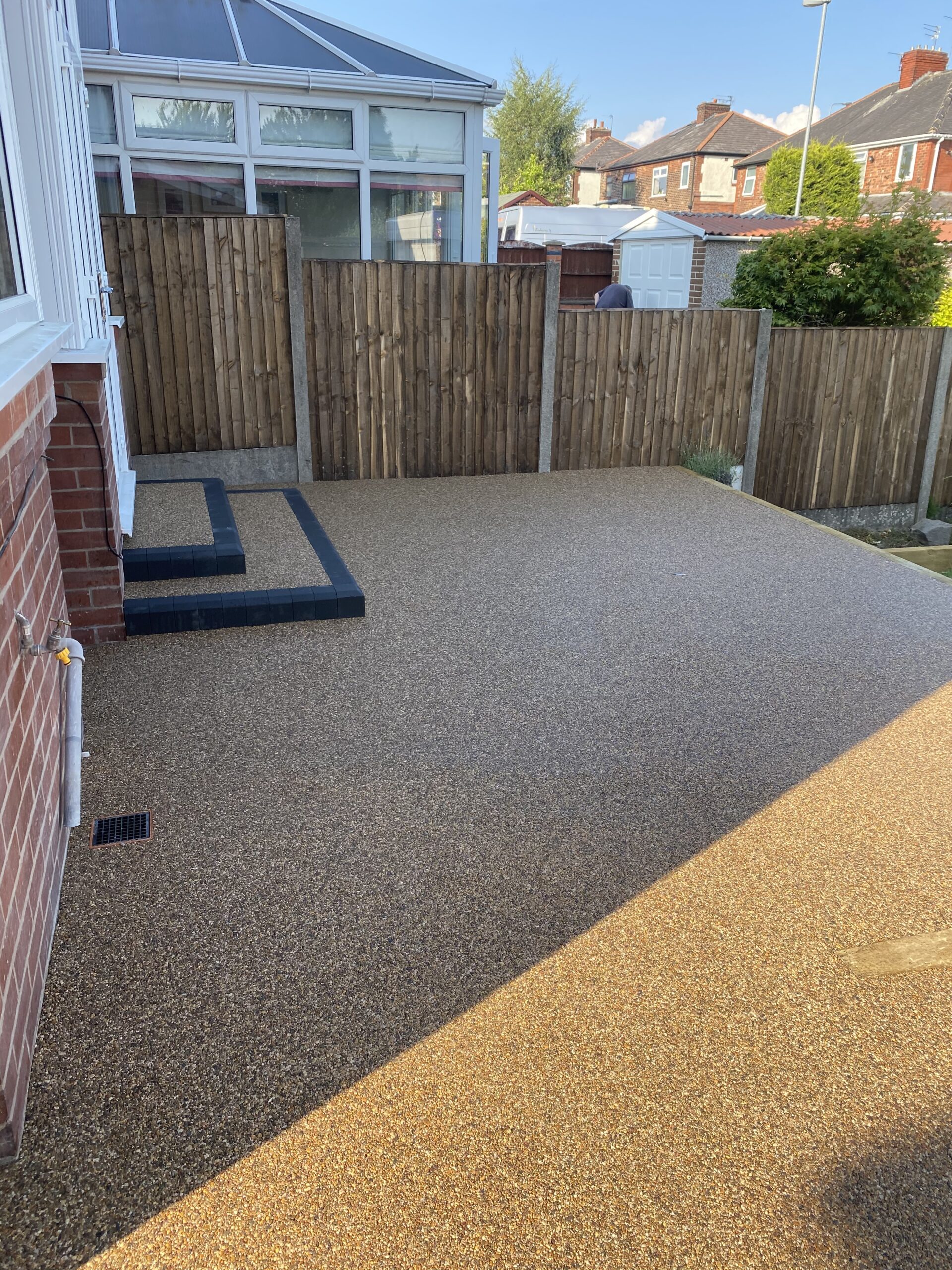 Completed Cappuccino resin patio in Failsworth with new charcoal-edged steps and a sleeper border