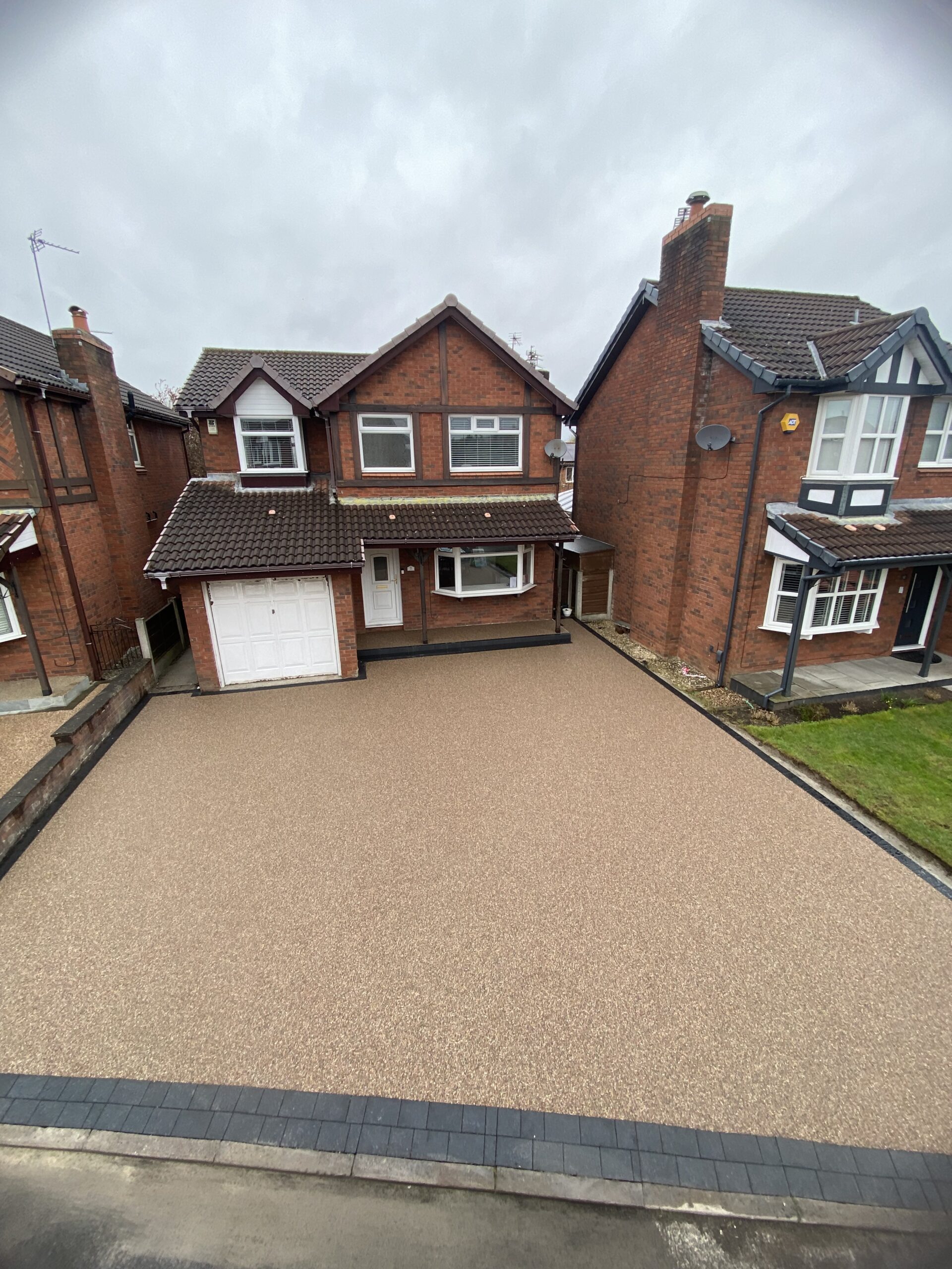 Finished warm-toned resin driveway in Dukinfield with dark block border