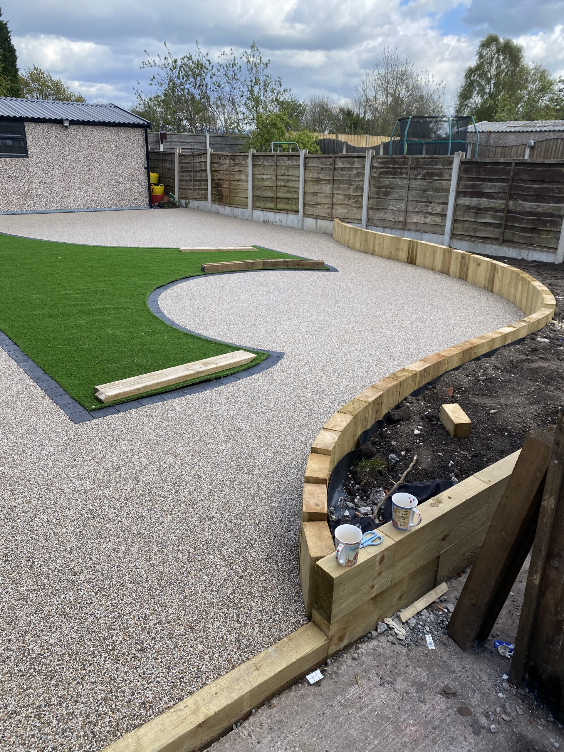 Curved Aurora resin patio with raised sleeper planters in Heaton Chapel, Stockport