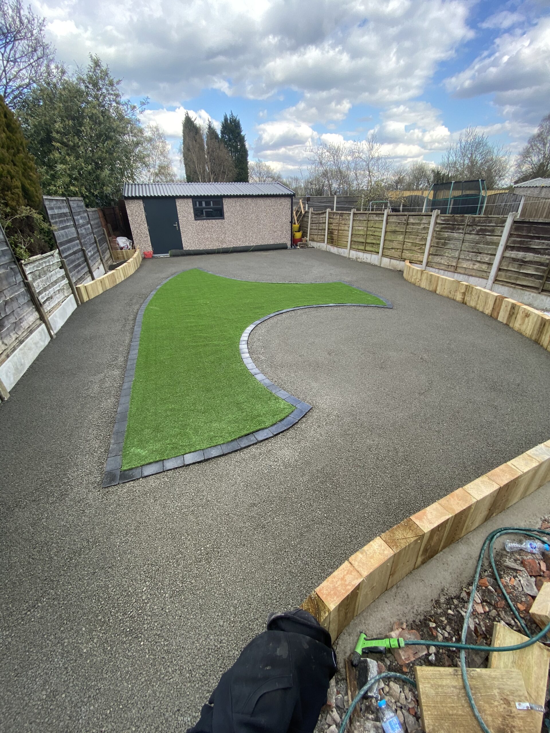Finished resin patio garden with curved artificial grass area and charcoal edging in Heaton Chapel