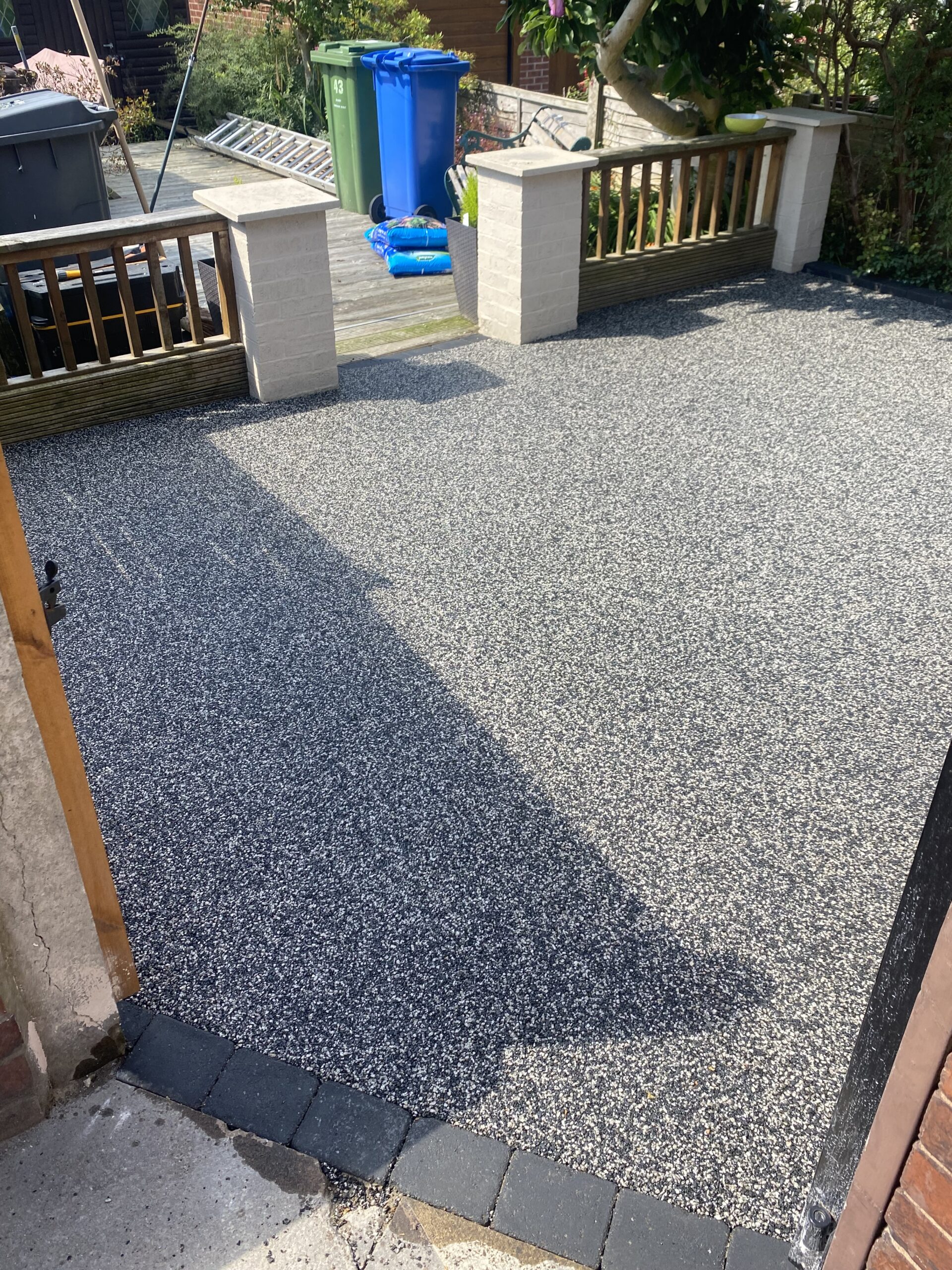 Eclipse resin patio in Hyde viewed from the house, showing the finished surface beside existing raised timber decking