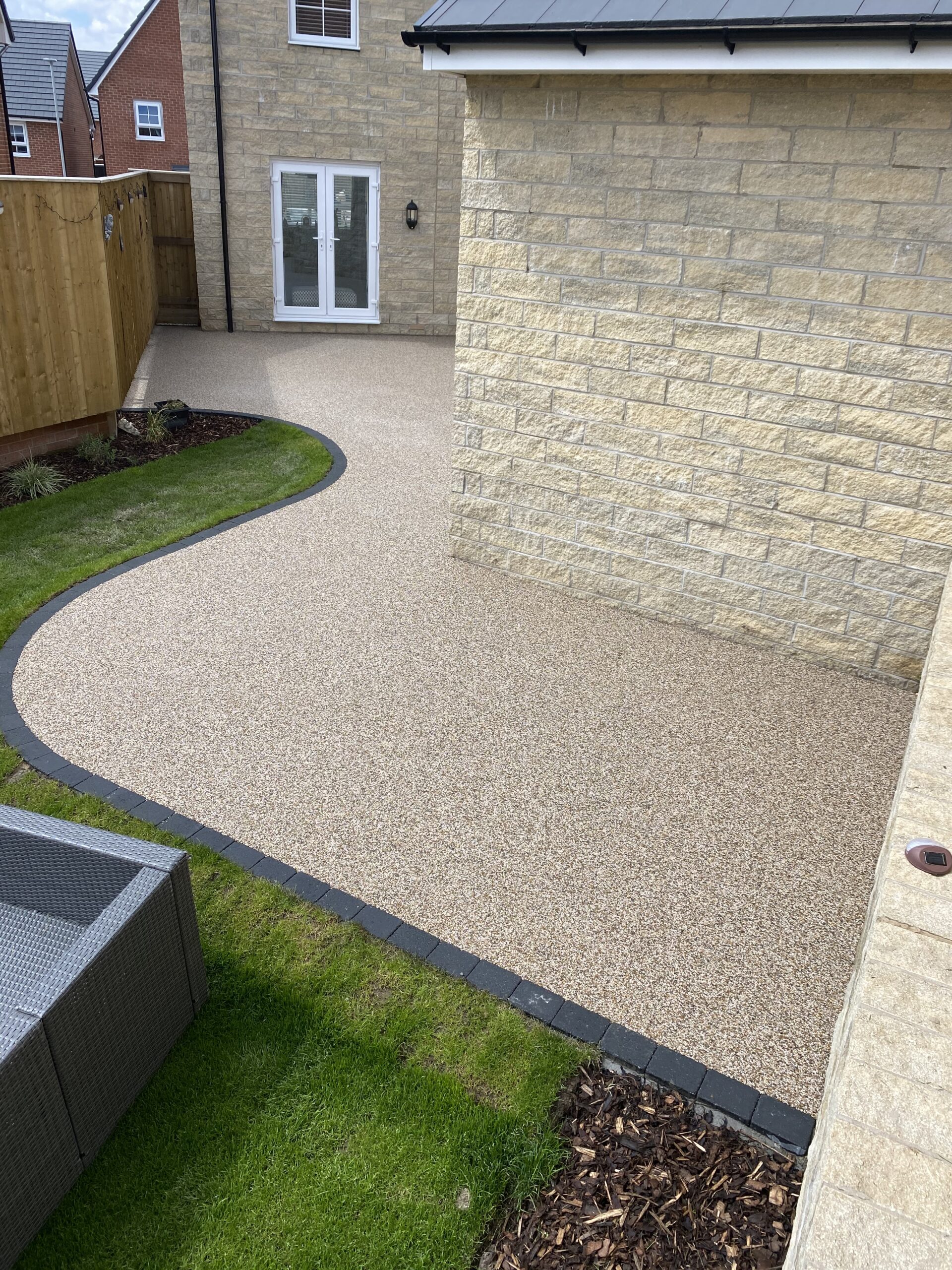 Curved charcoal block border around Arizona resin patio in Hattersley