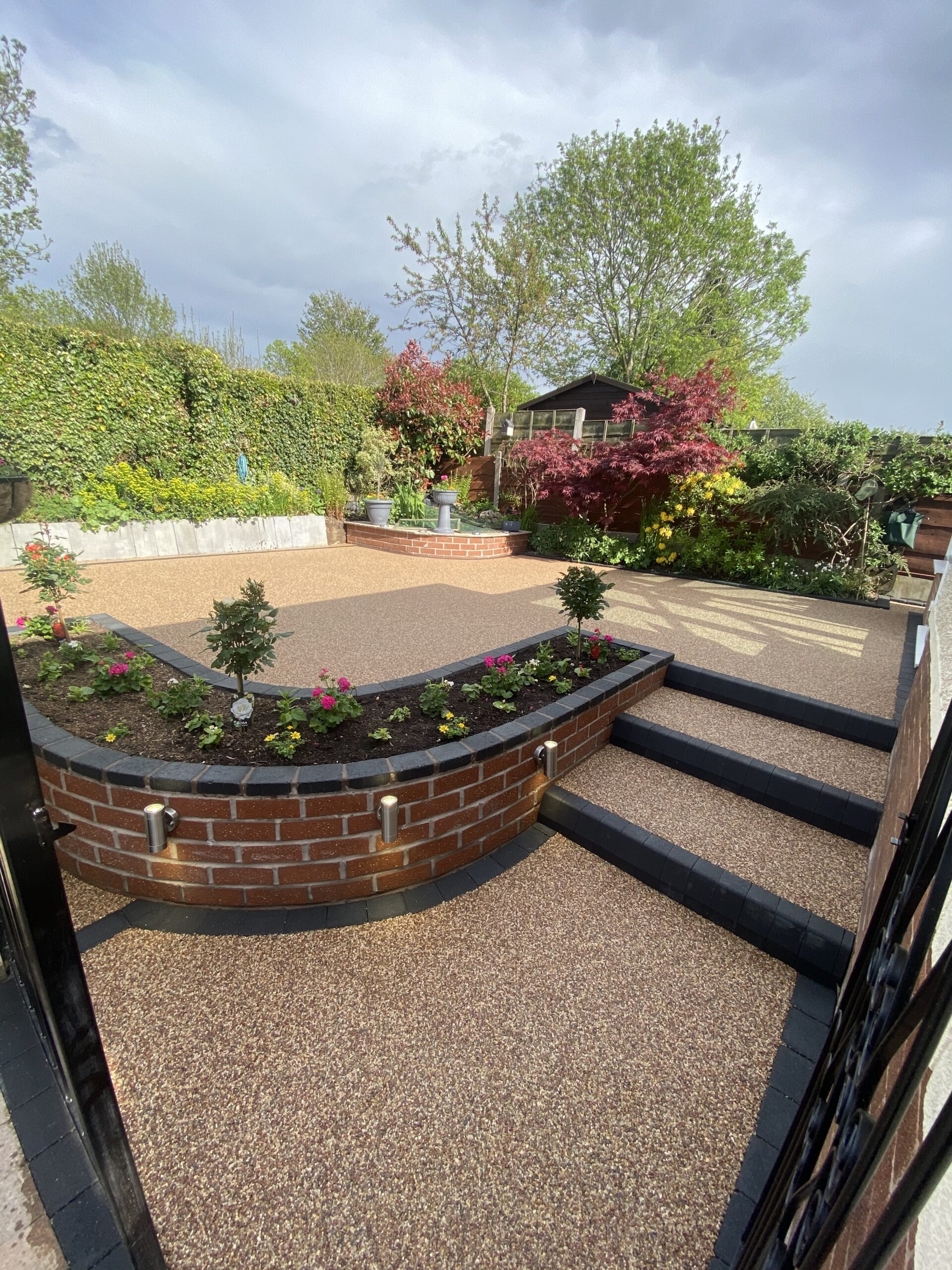 Finished 36m² Sienna resin patio in Bredbury with charcoal edging and raised flower beds
